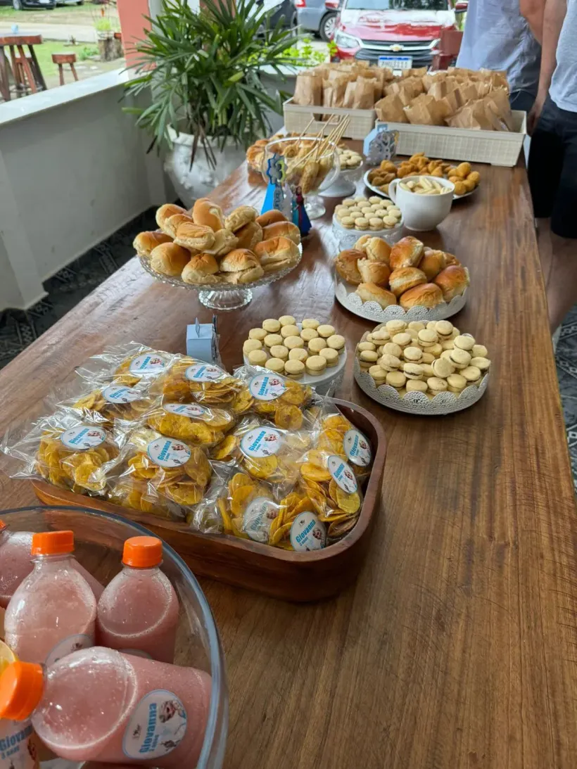 Uma mesa repleta de vários petiscos e bebidas; pães, biscoitos e sucos são visíveis - Solar Café e Pousada
