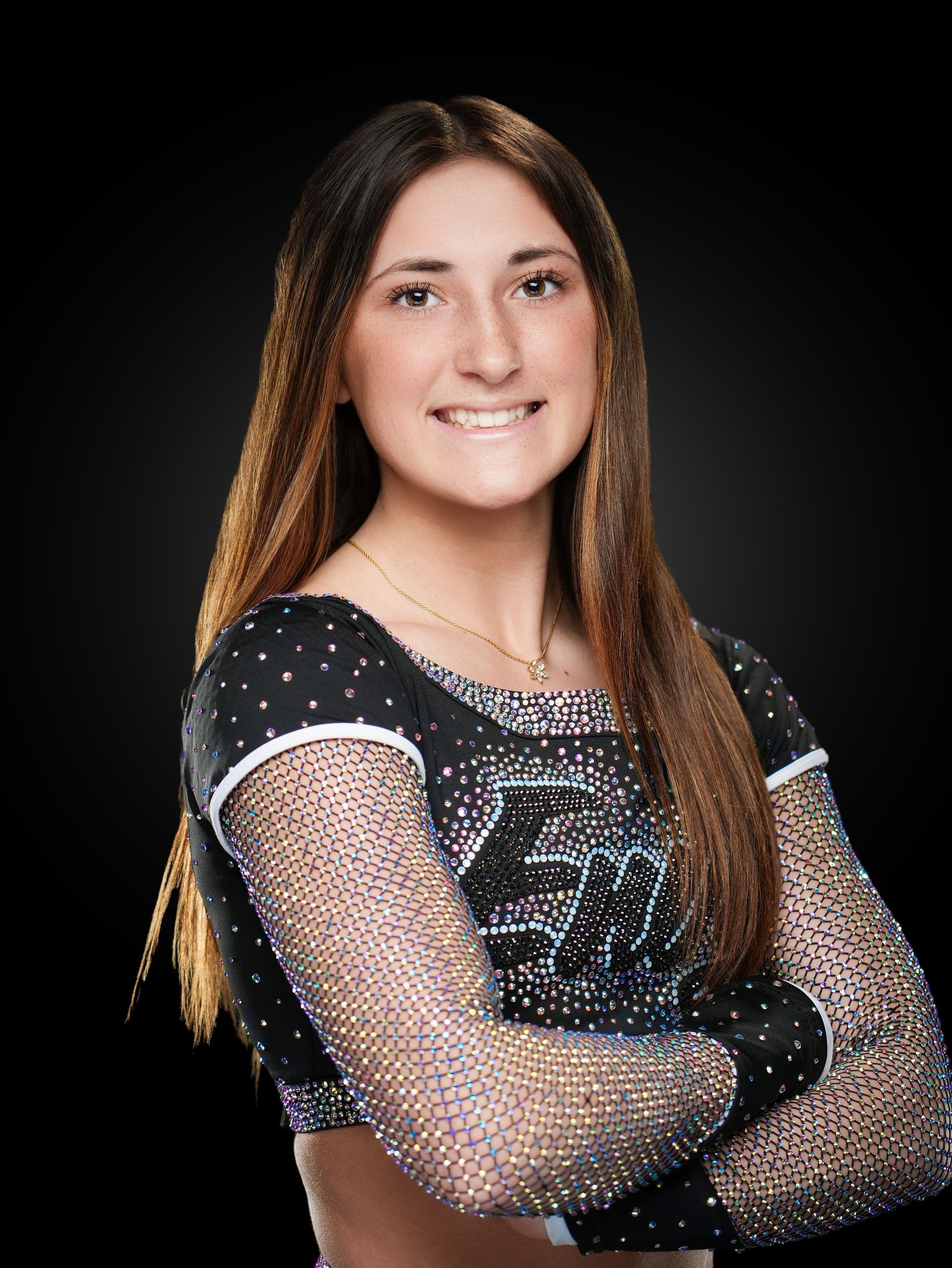 Portrait of a smiling person in a black sequined outfit, arms crossed against a black background