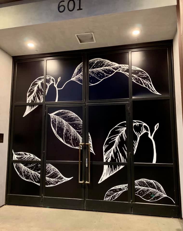 A black door with white leaves painted on it