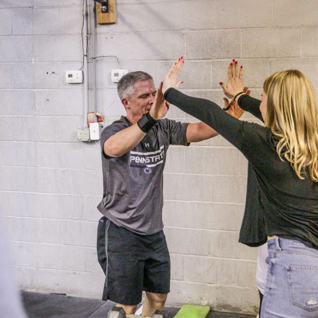 A man and a woman are giving each other a high five in front of a brick wall.