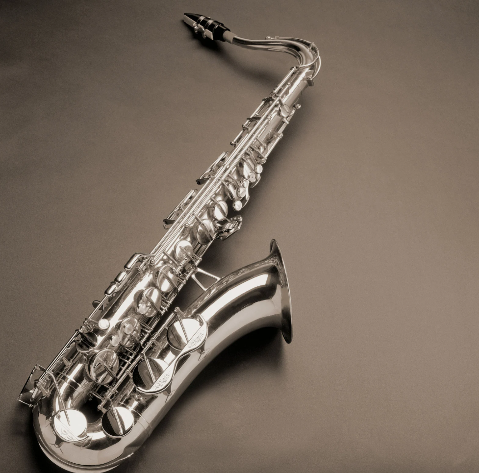 A silver saxophone is sitting on a brown surface