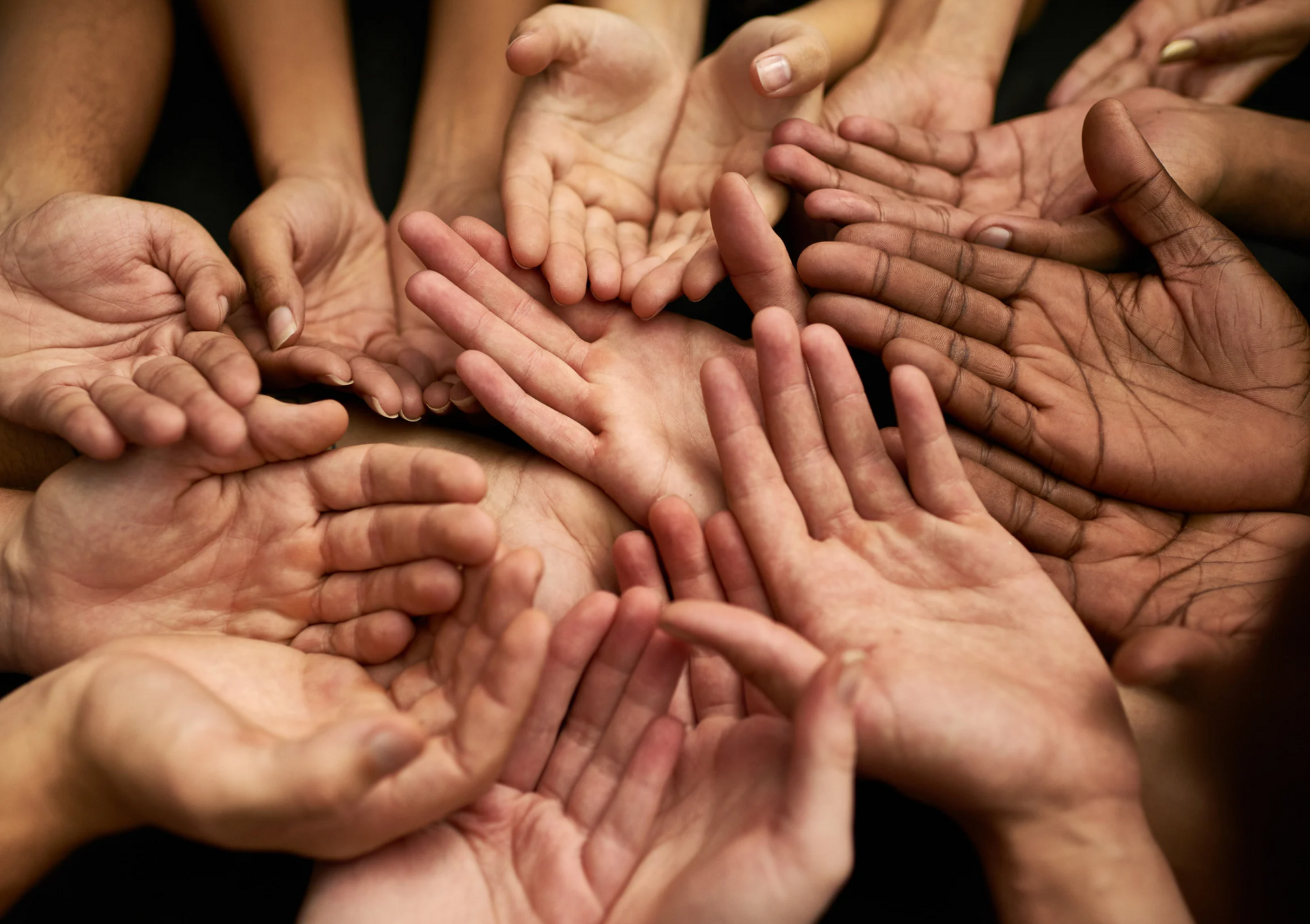A group of people are putting their hands together in a circle.