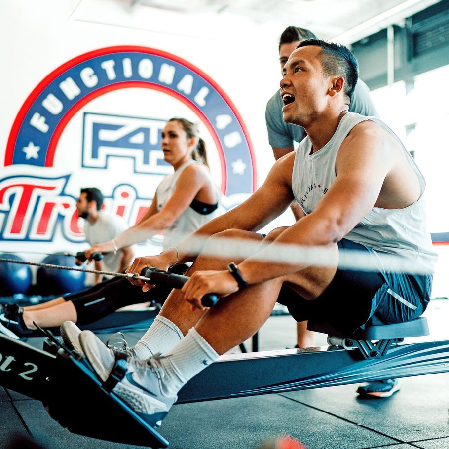 People rowing on indoor machines in a gym, with a functional training logo in the background