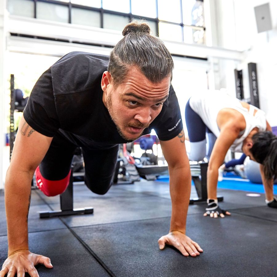 People doing plank exercises in a bright gym, focused on a workout session