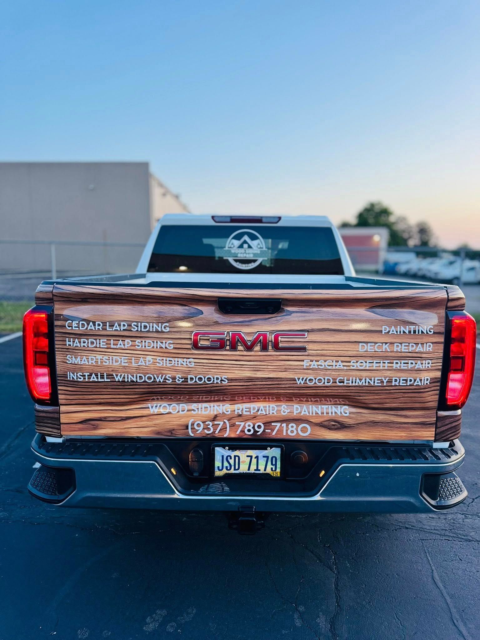 GMC truck with wooden bed design and business contact information. License plate: RI 7770.