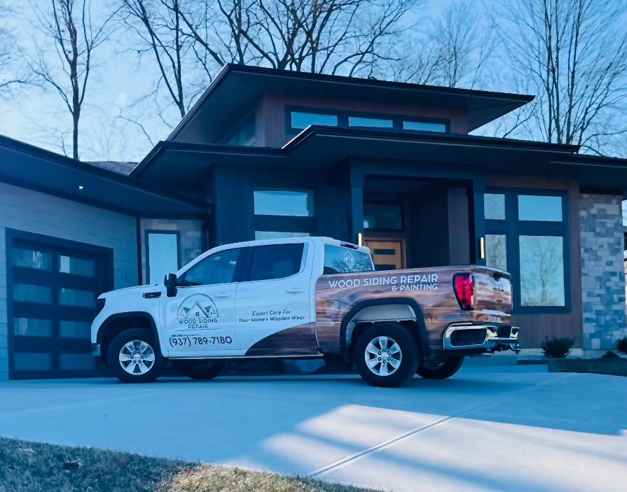 White pickup truck with business graphics parked in front of a modern house.