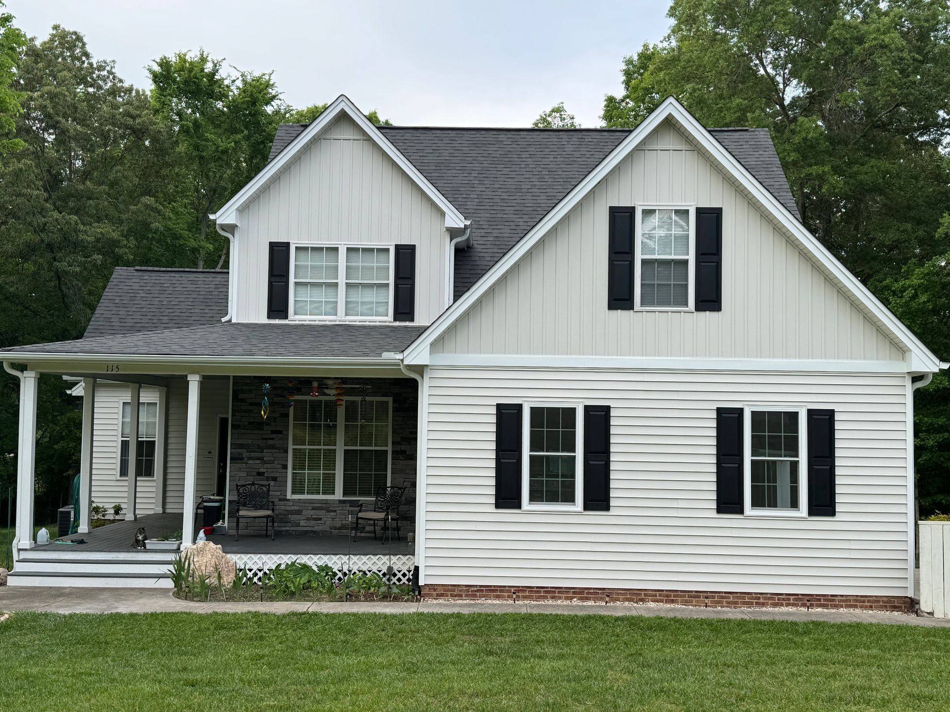 A white house with black shutters and a porch