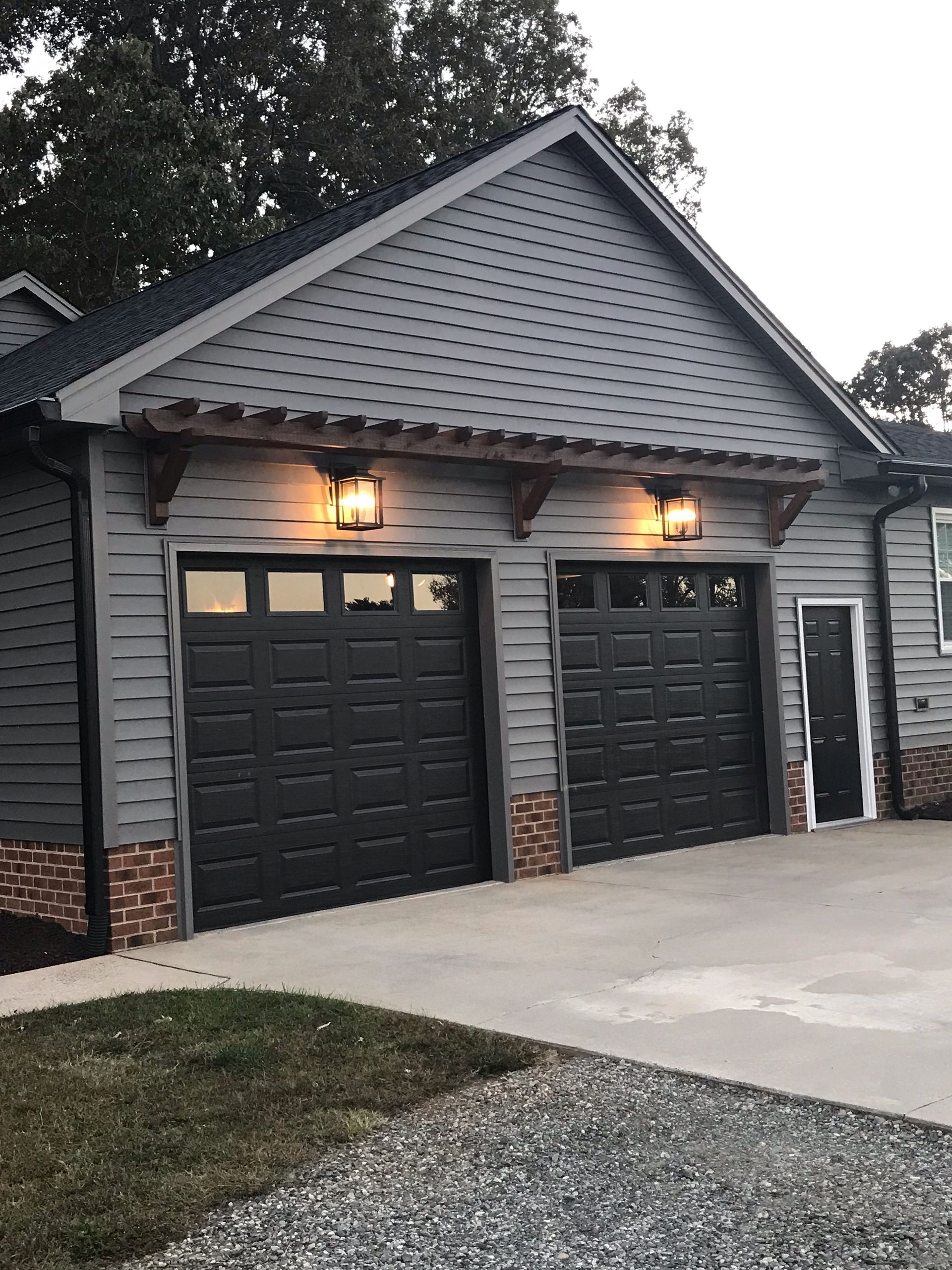 A gray house with black garage doors and a driveway