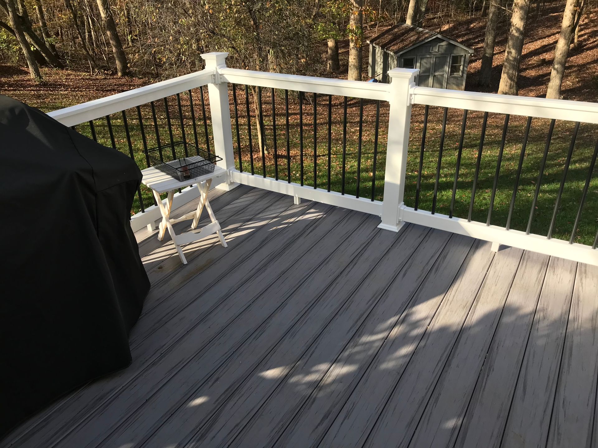 A deck with a grill and a table on it.