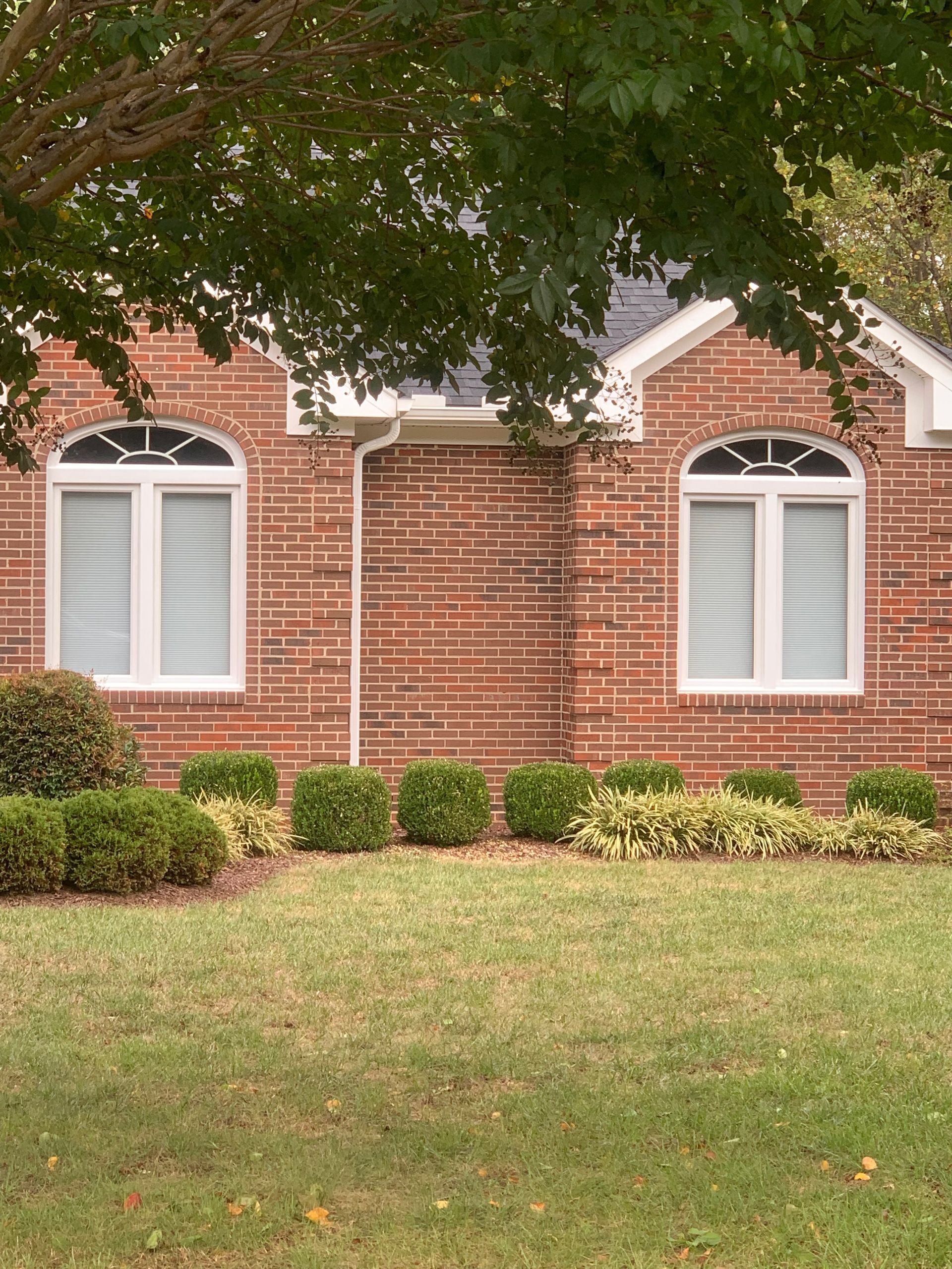 A brick house with white trim and arched windows