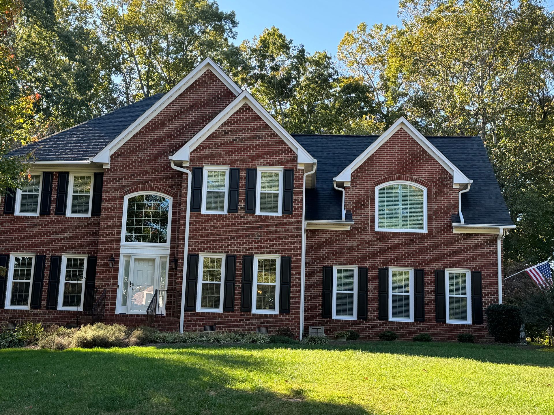 A large brick house with a black roof and white shutters