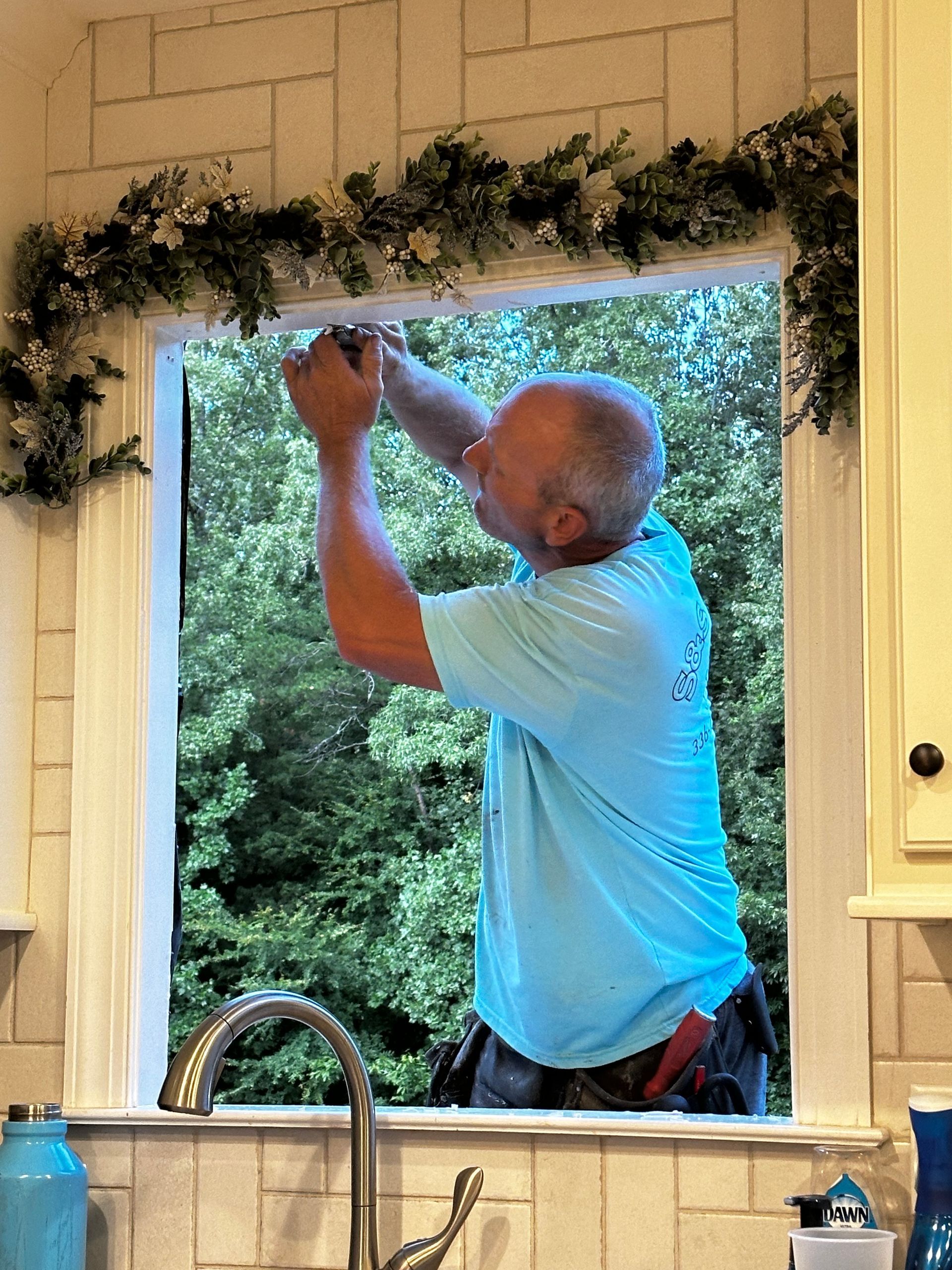 A man in a blue shirt is working on a window