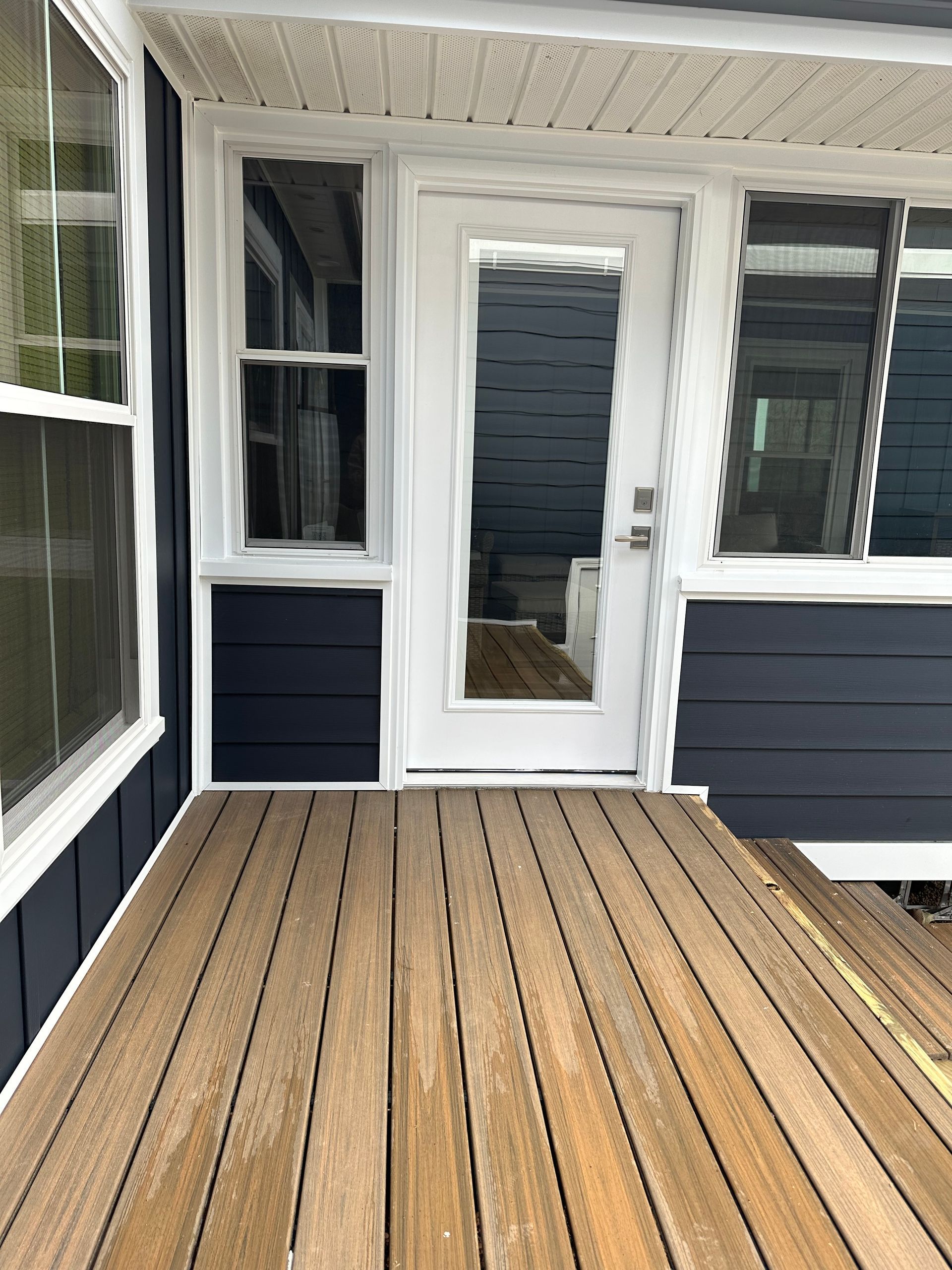 A porch with a wooden deck and a white door