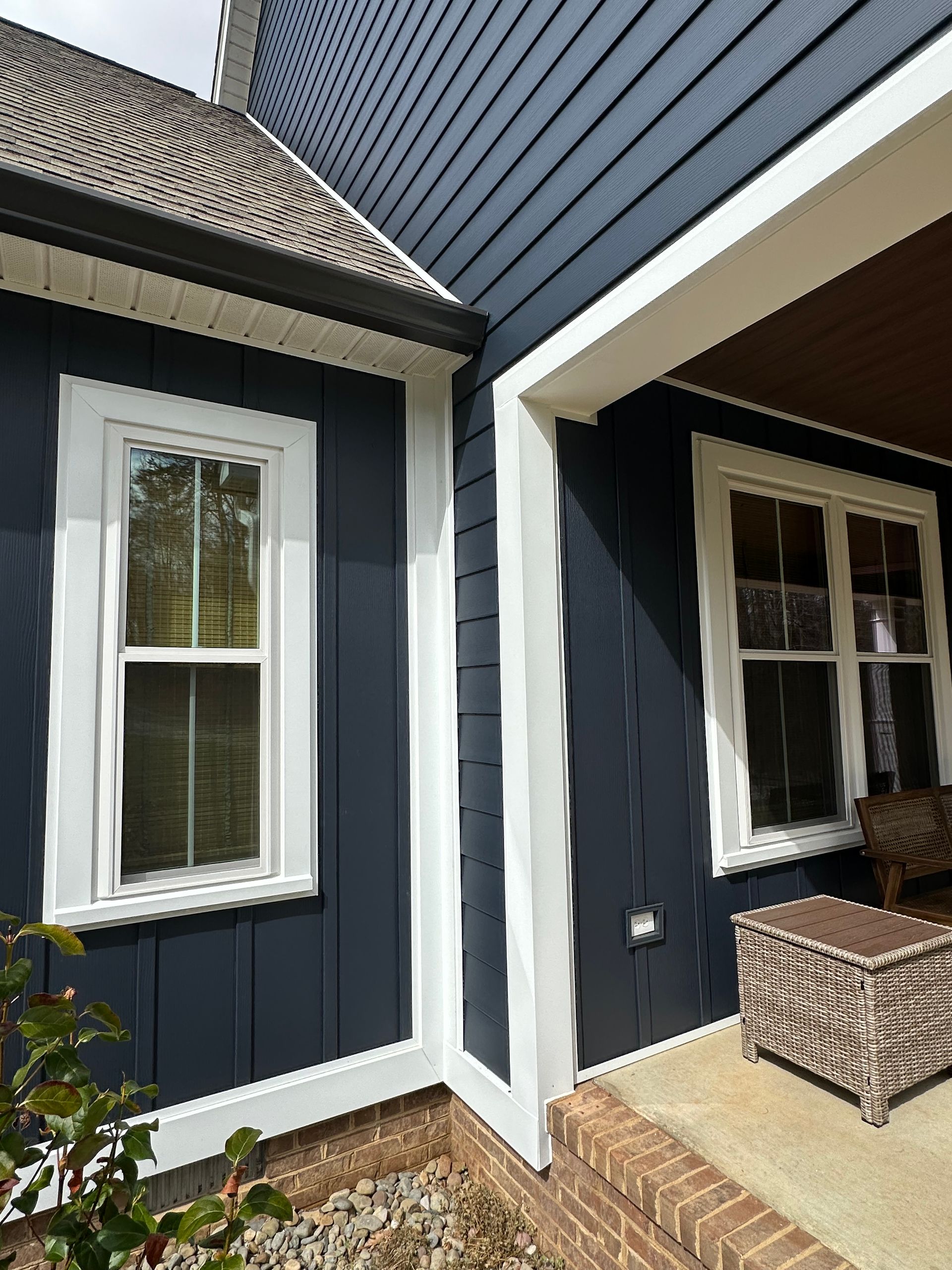 A blue house with white trim and windows and a porch.