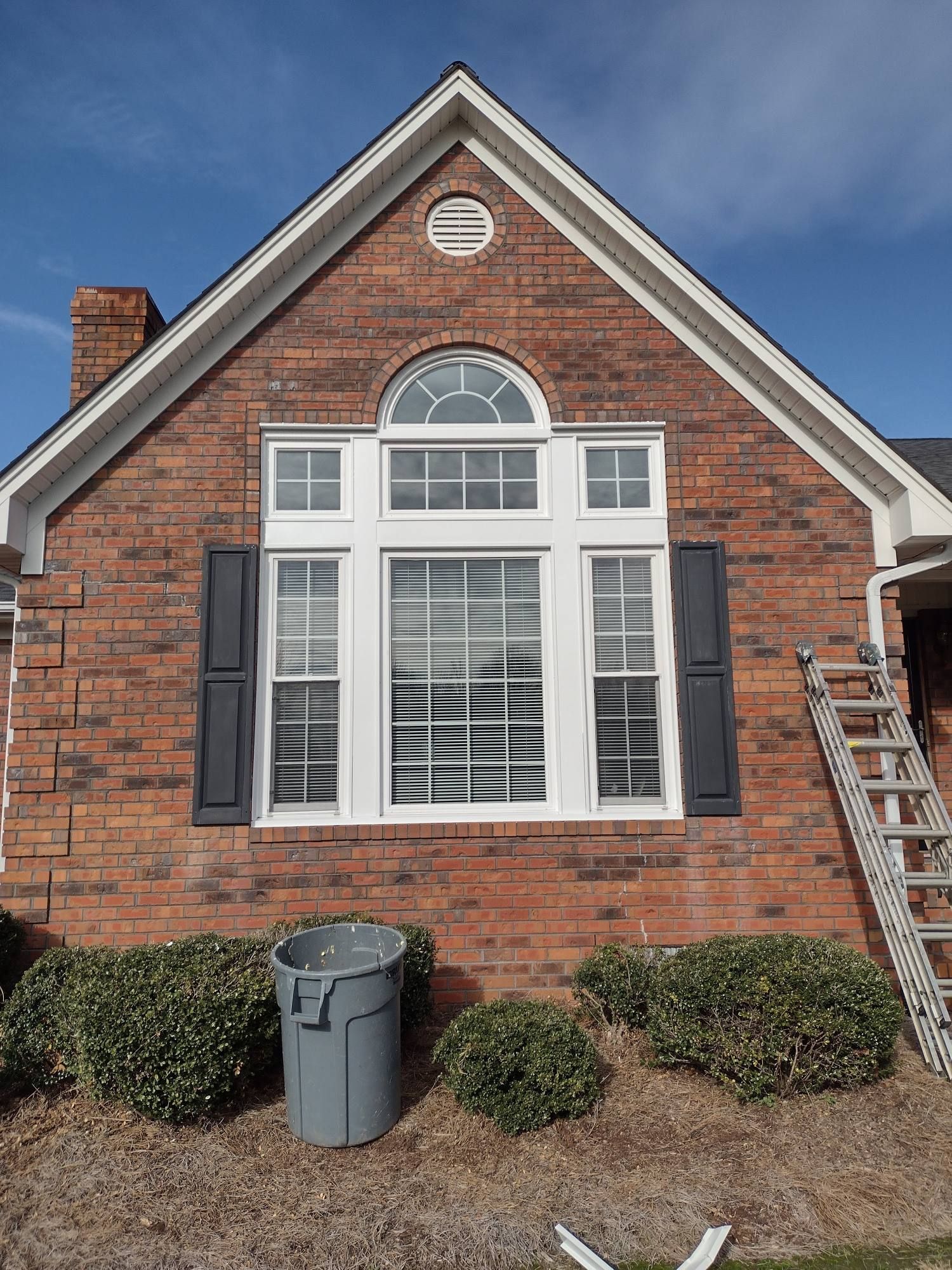 A brick house with a large window and black shutters