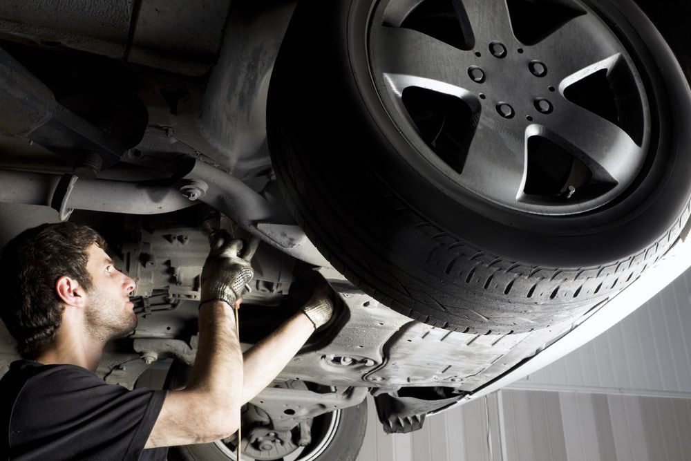 A Man is Working Under a Car in a Garage — Secure Diesel & Automotive in Boulia, QLD