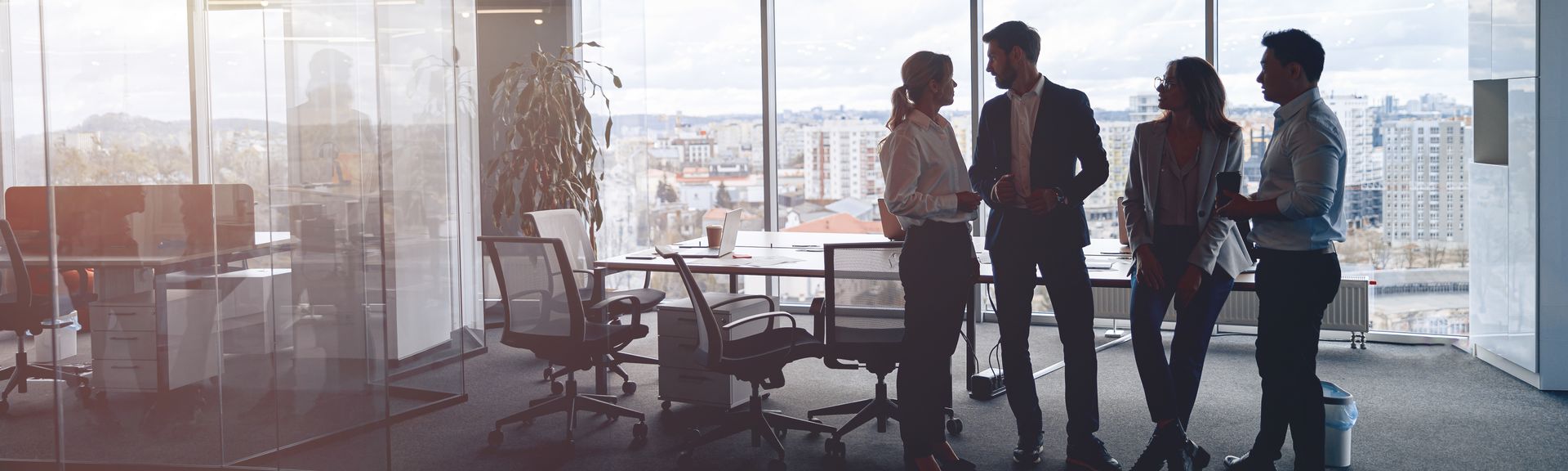 Business team in an office by a large window, discussing work.