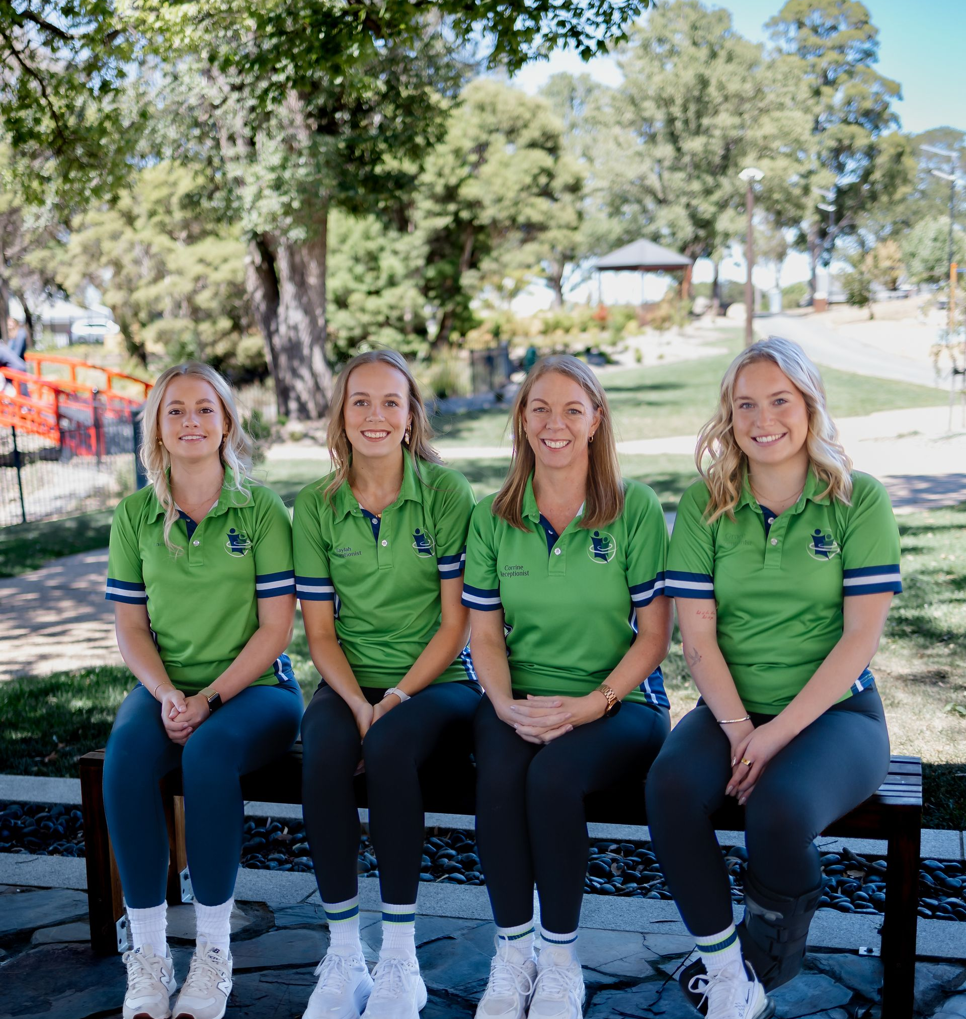 Four People in Blue Sweatshirts Stand in Front of a Storefront — Goulburn Physiotherapy Centre in Goulburn, NSW