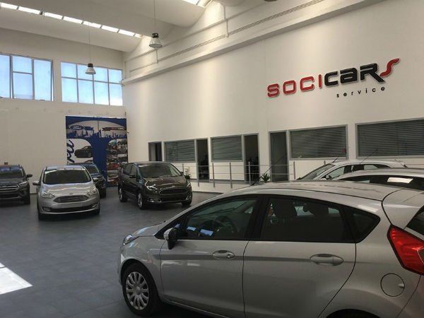 Autosalone con diverse auto parcheggiate e un'insegna 
