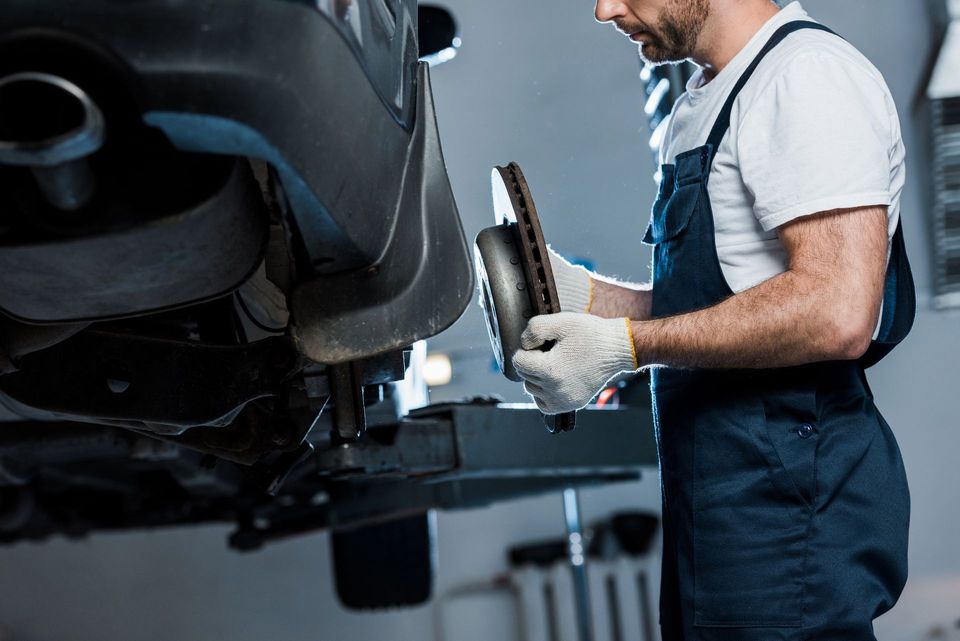 Un meccanico utilizza un attrezzo per la pinza del freno su un'auto in un'officina.