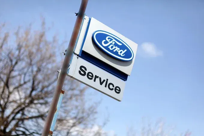 Cartello di servizio Ford contro un cielo azzurro, inclinato su un palo