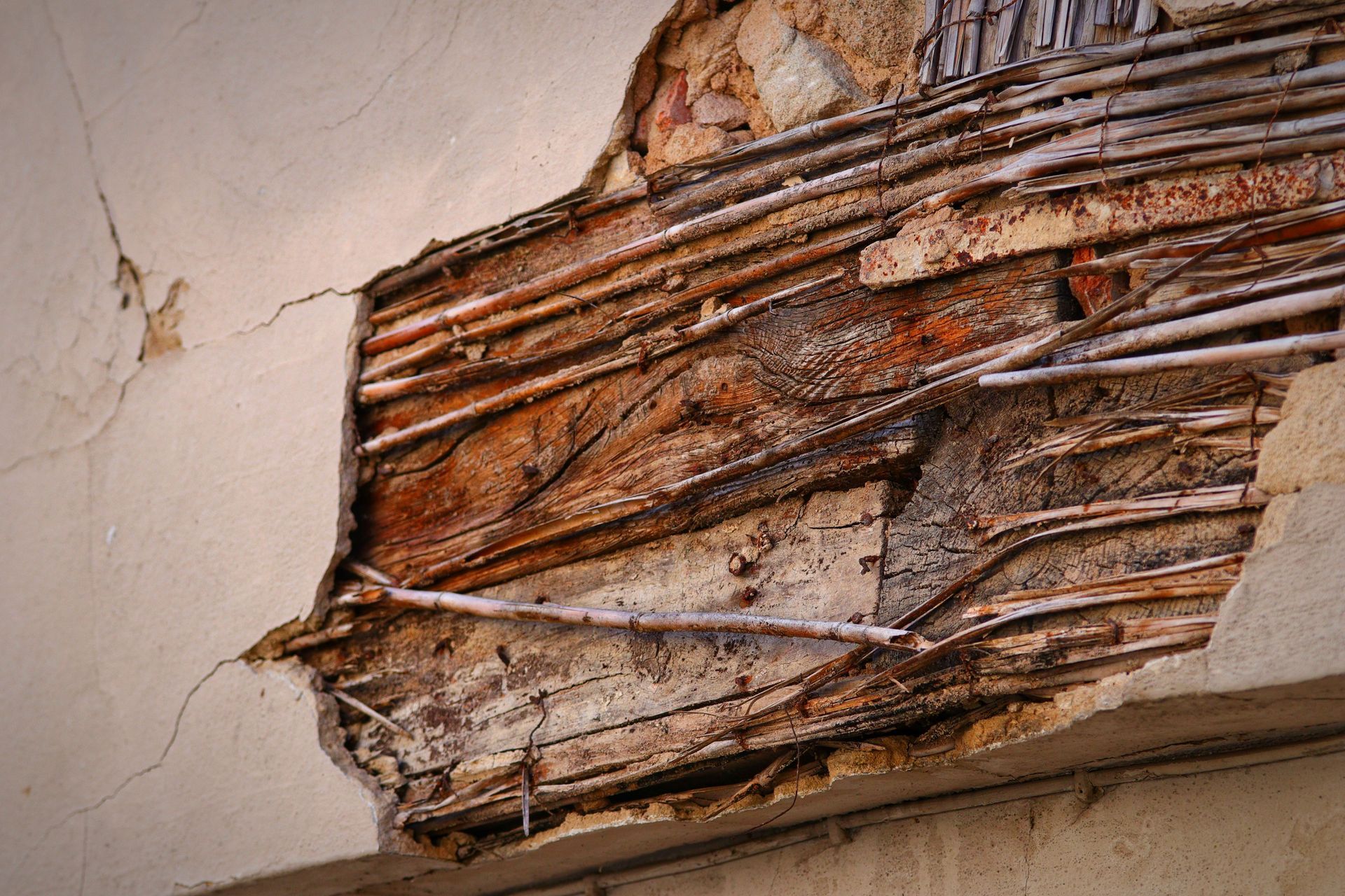 Severely damaged wall with exposed wooden lath and cracked plaster