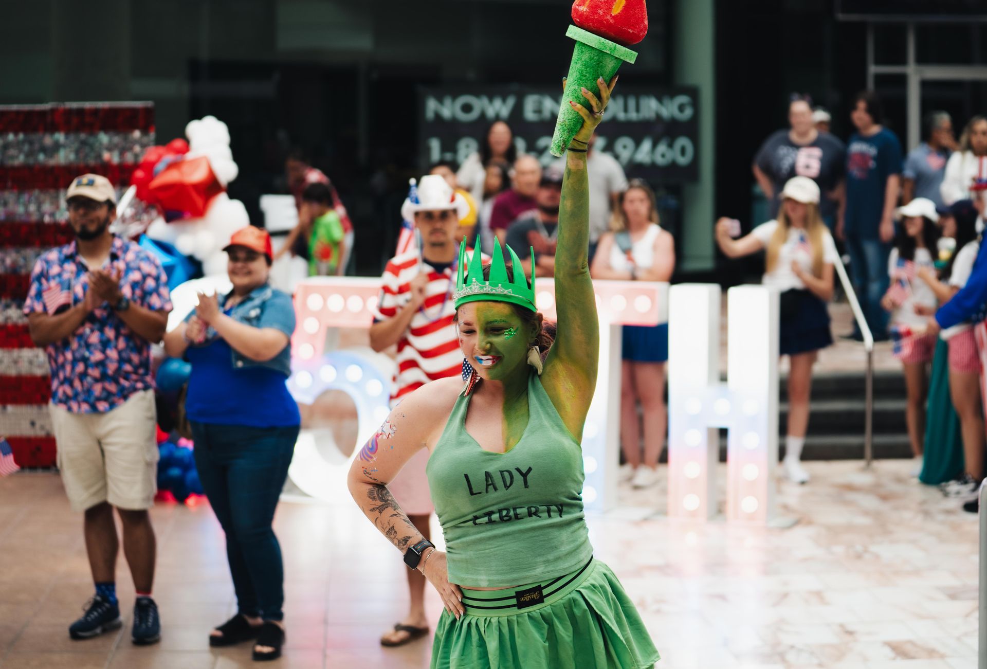 Costumed performers posing indoors, including a person in green with a tall hat in the foreground
