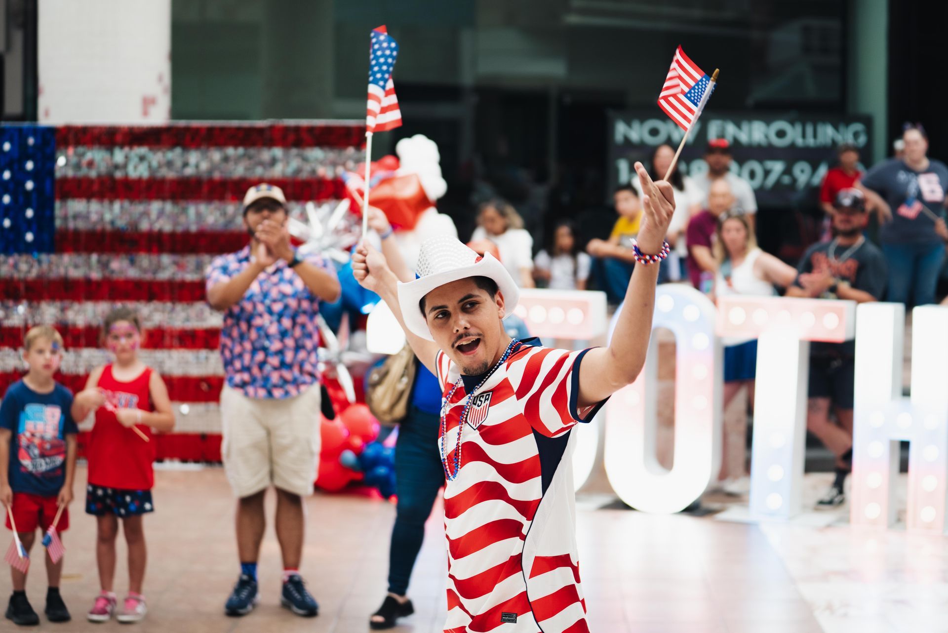 Child waving an American flag in a red-and-white striped outfit at a patriotic event