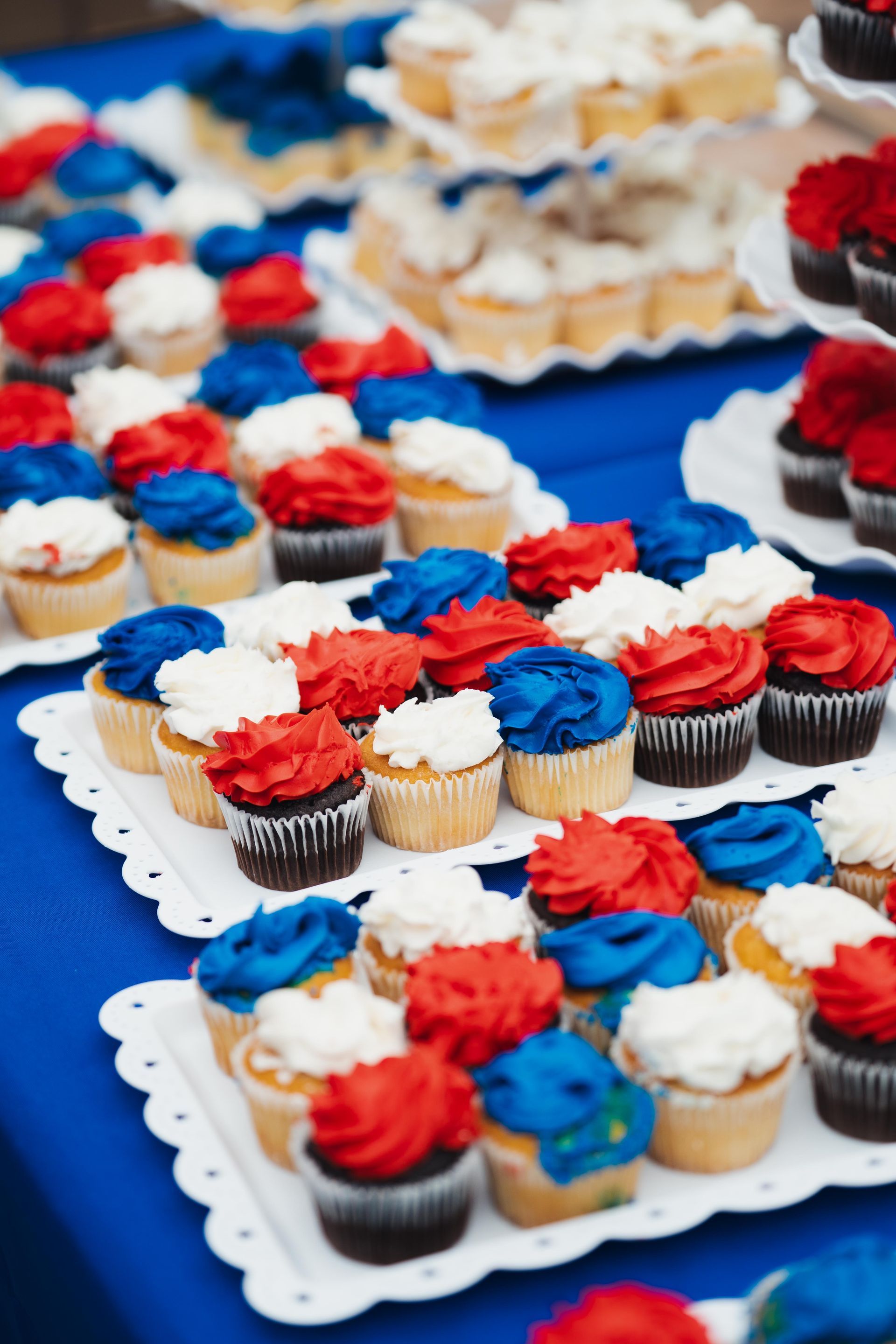 Trays of cupcakes with red, white, and blue frosting at a party table