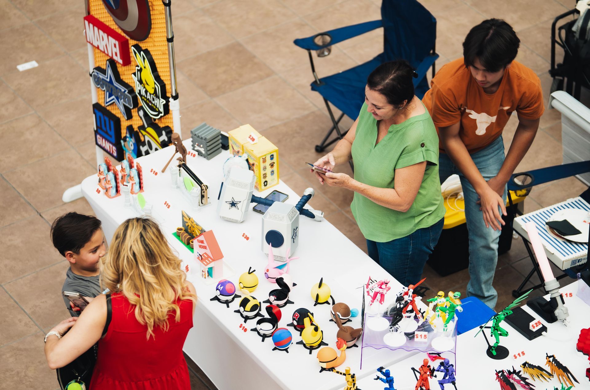 People browsing a colorful tabletop display at an indoor craft fair