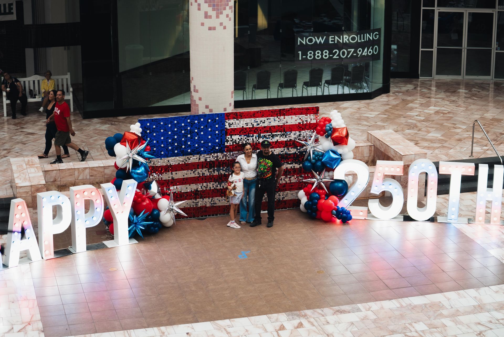 People posing by a U.S. flag display with balloons and large 
