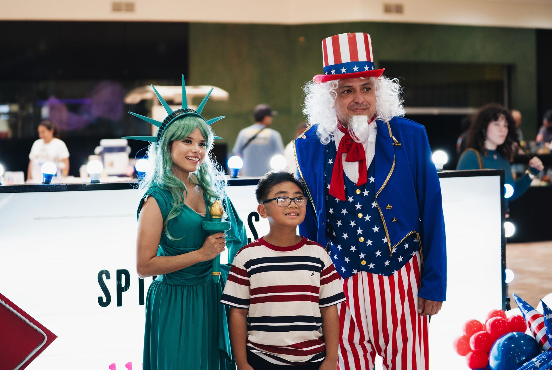 Child posing with Statue of Liberty and Uncle Sam characters at an indoor event