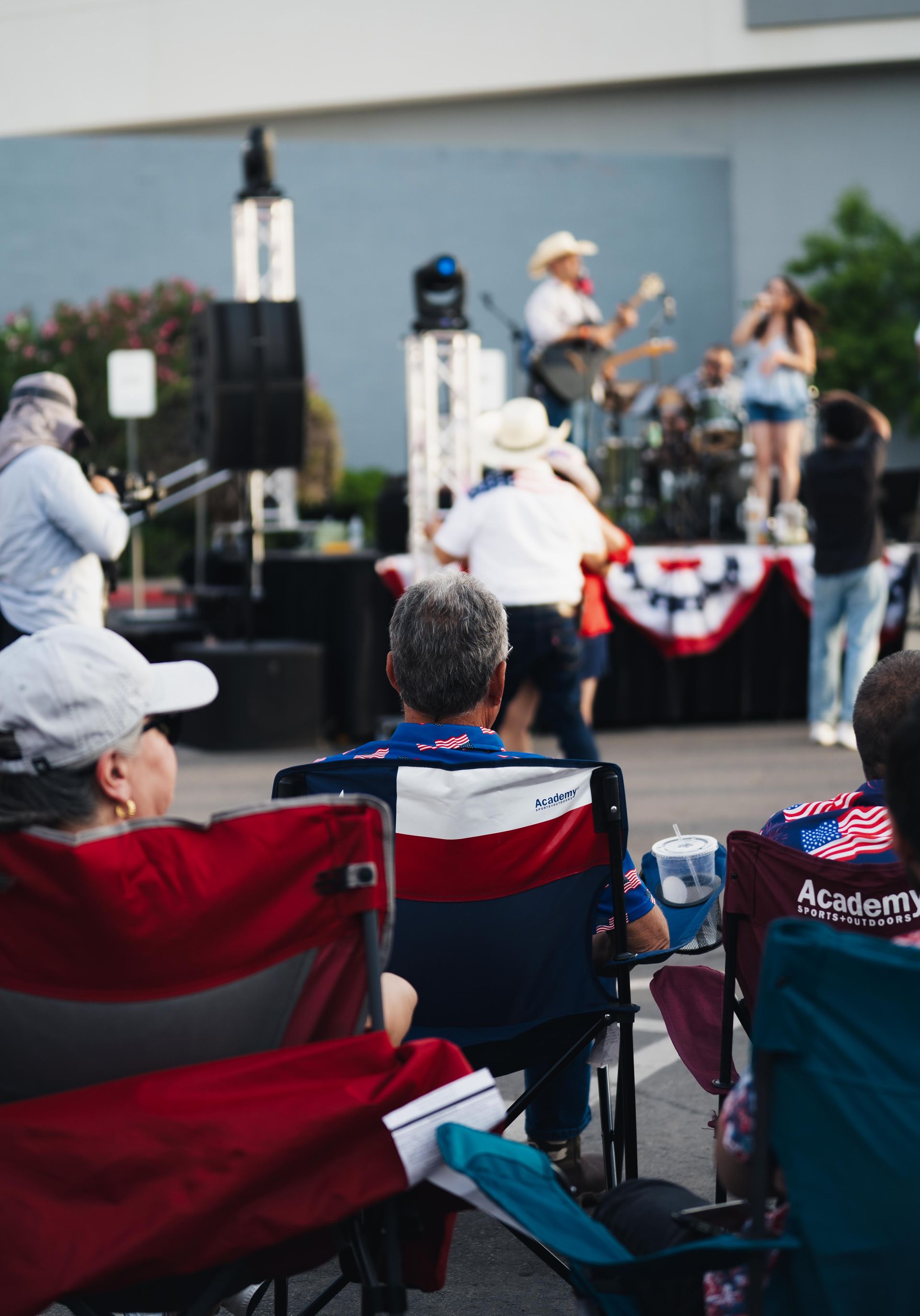 Outdoor concert with seated audience watching a live band on a small stage.