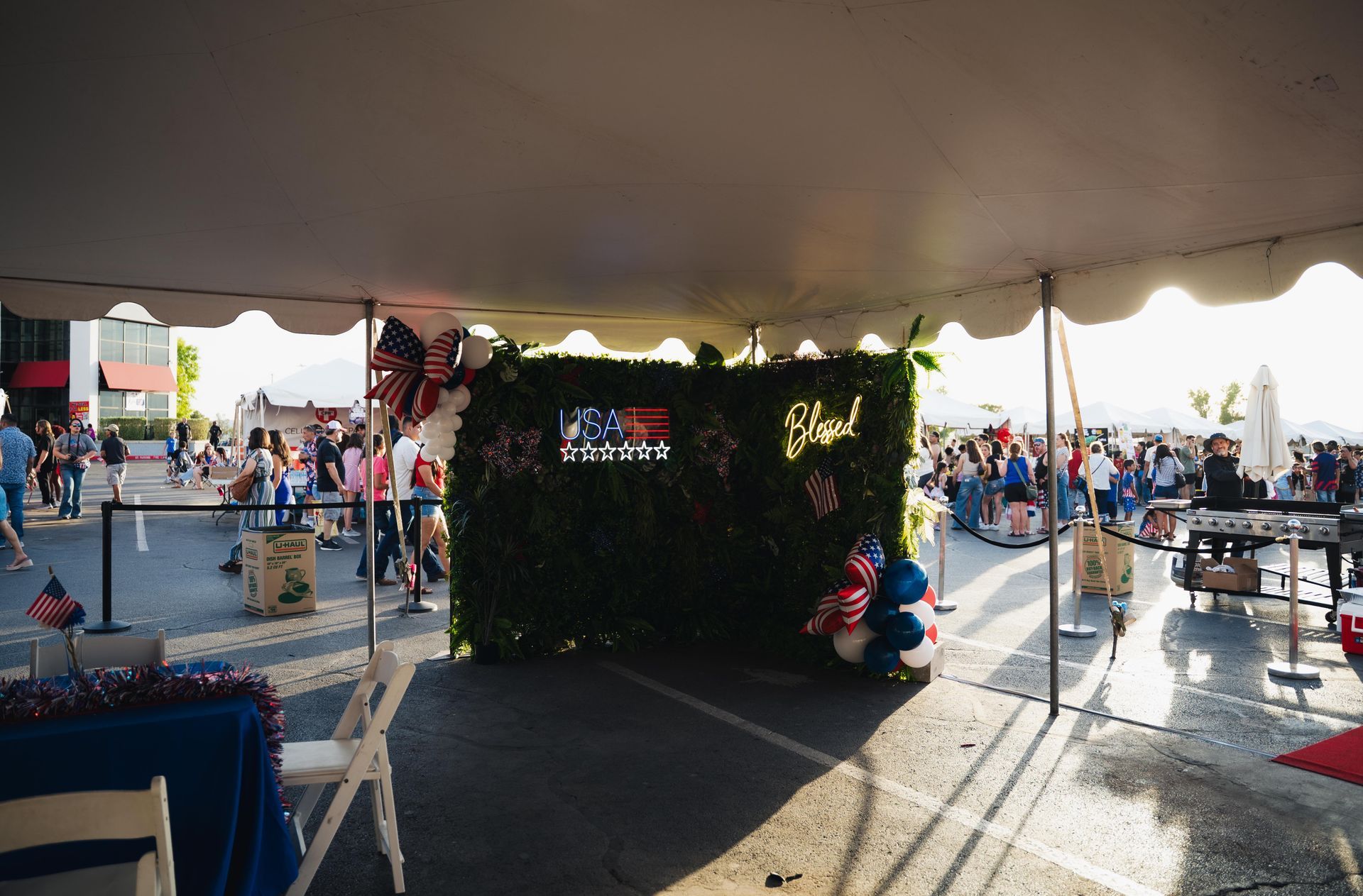 Outdoor event under a tent with a holiday-decorated booth and a crowd in the background