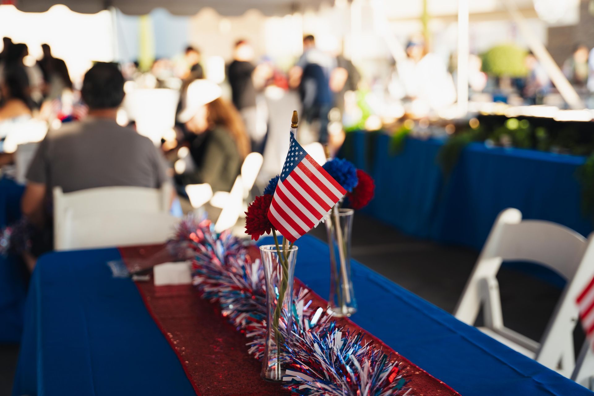 Red, white, and blue patriotic table display with small American flags at a busy outdoor event