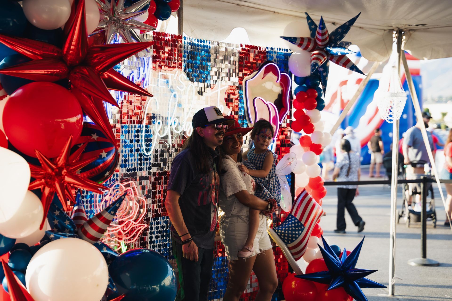 People posing amid red, white, and blue star decorations at a festive outdoor event