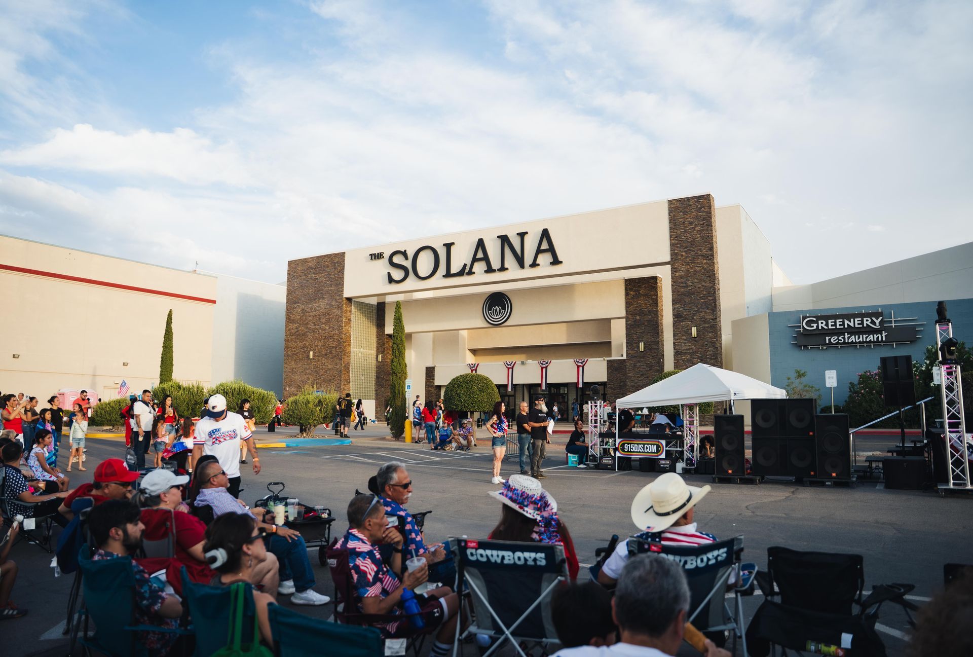 Crowd seated outdoors in front of the Solana shopping center during a live event at dusk