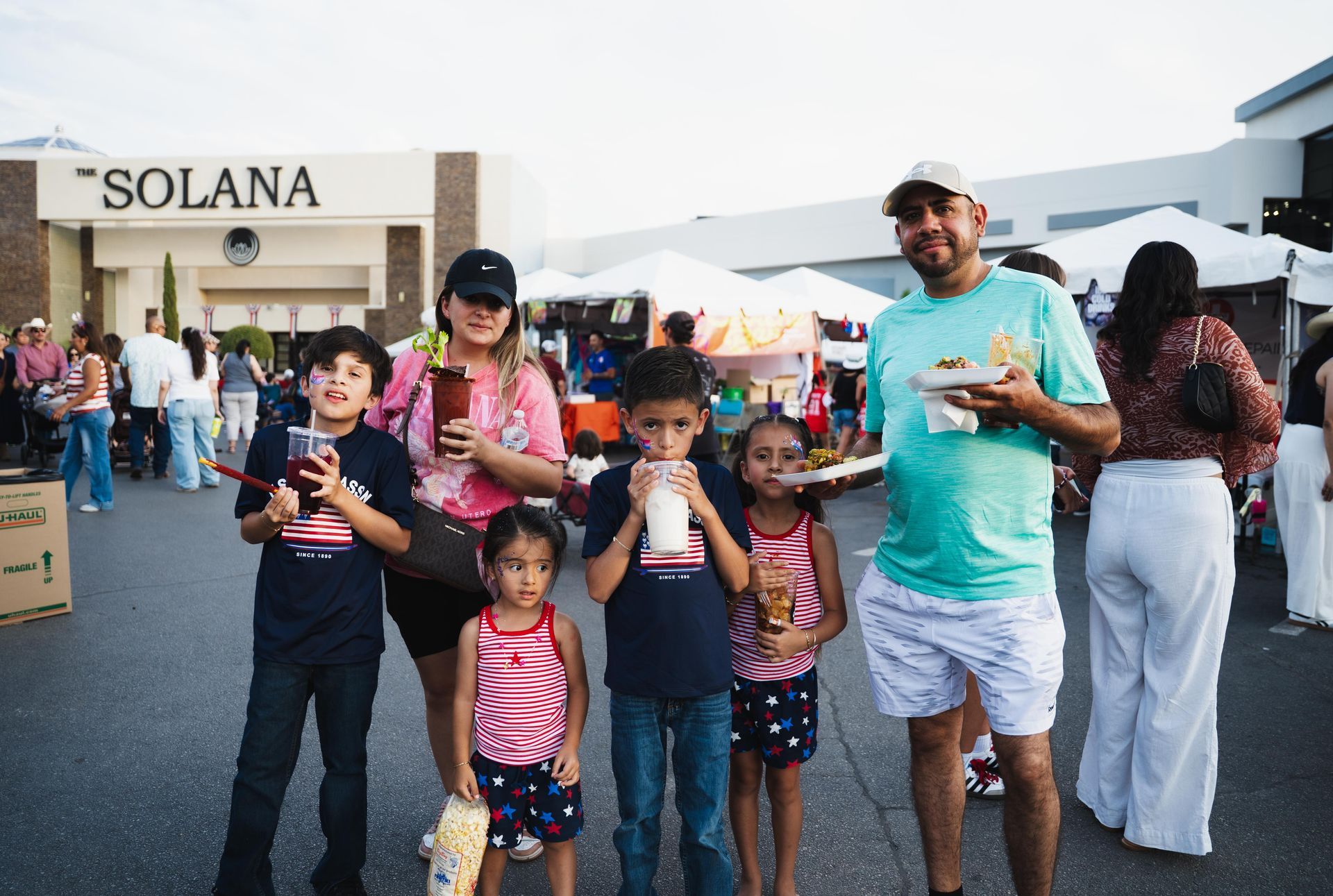 Group of people holding drinks outside a Solana-branded booth at an outdoor event