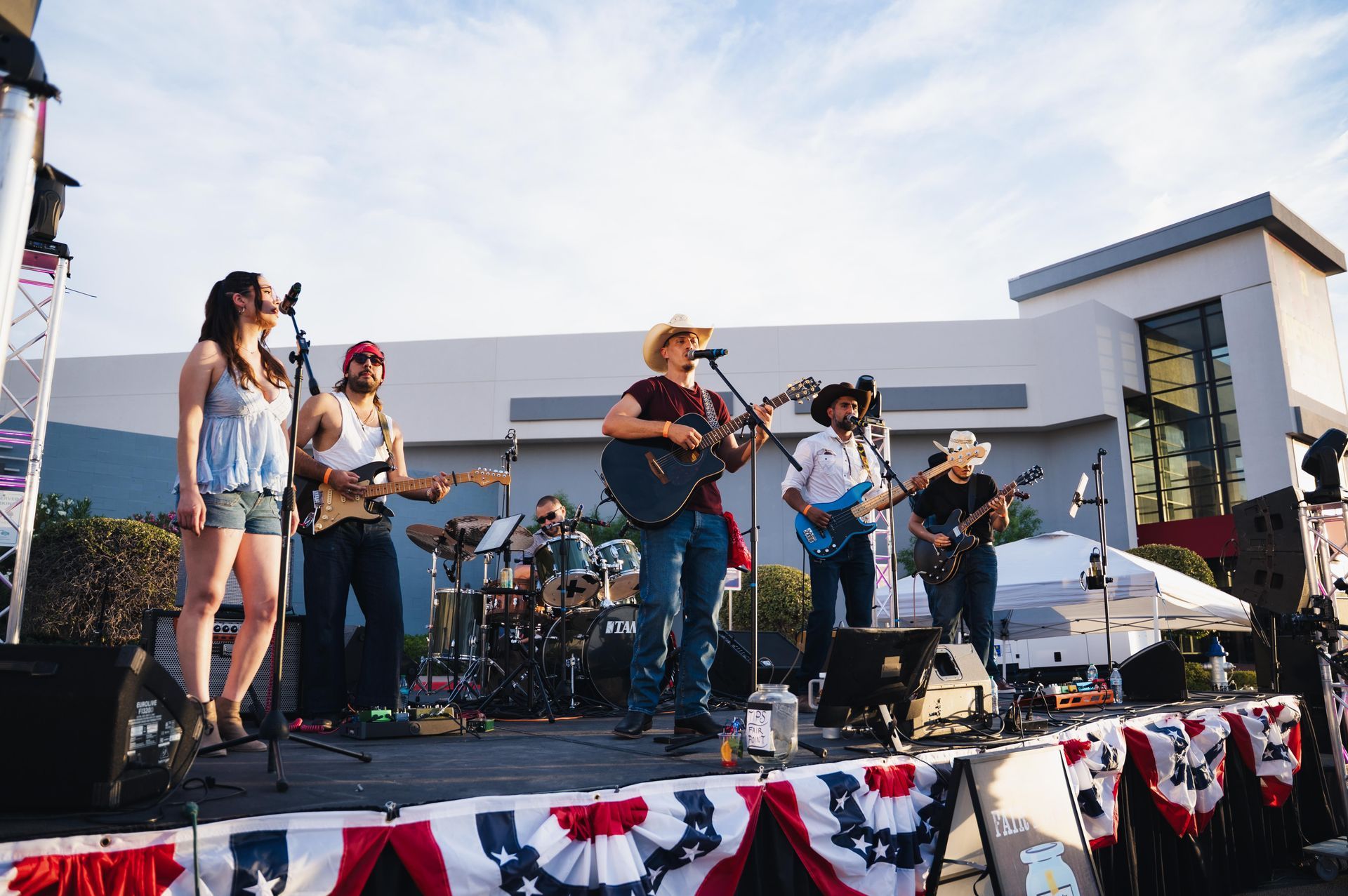 Live band performing on an outdoor stage decorated with red, white, and blue bunting
