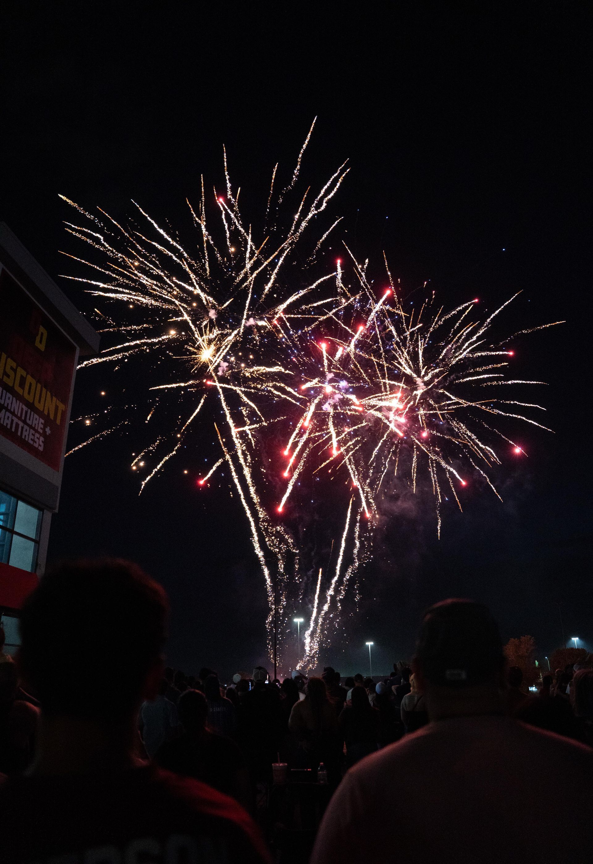 Fireworks bursting in a dark night sky above a crowd of silhouetted spectators