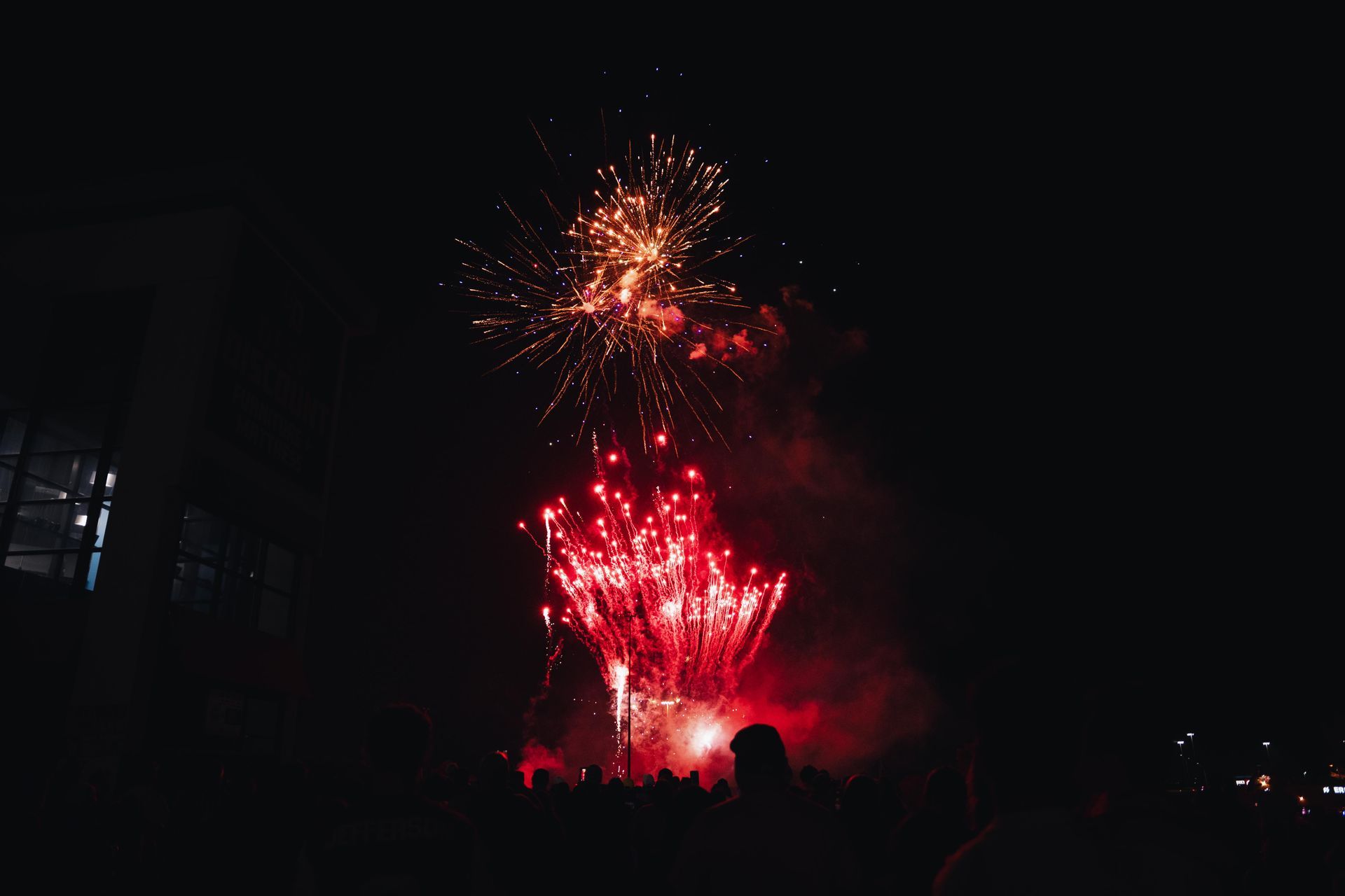 Red fireworks bursting over a dark crowd at night