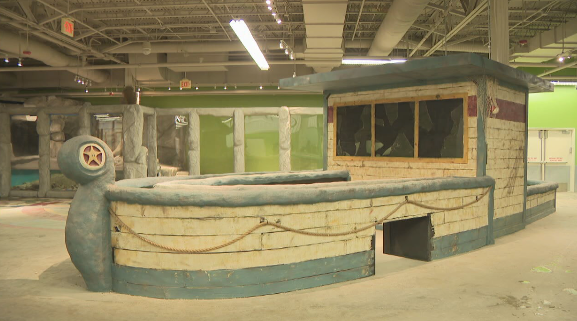 Indoor workshop with a large unfinished blue-and-beige mock building facade under construction