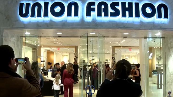Union Fashion storefront at night with bright sign and people gathered outside the glass entrance