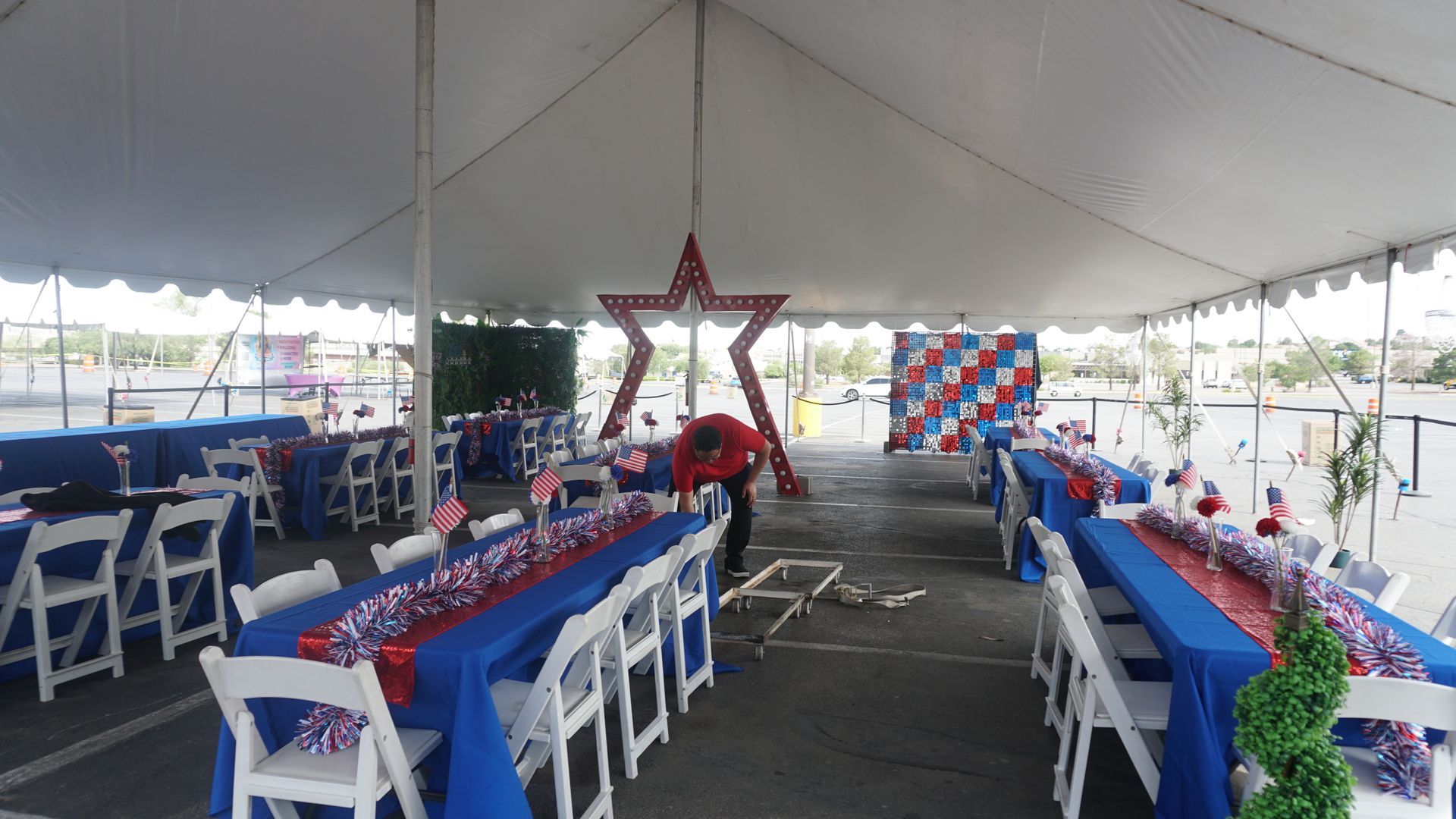 Decorated event tent with long tables, white chairs, and red-white-blue patriotic decorations