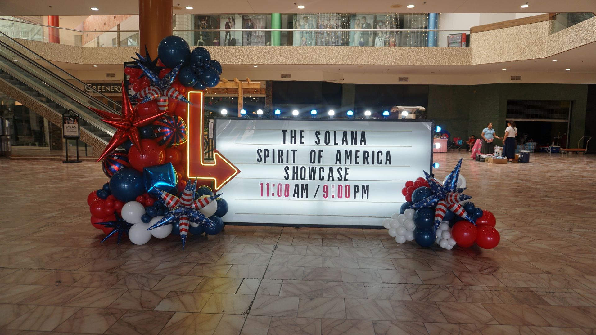 Mall sign for “The Sound Spirit of America” framed by red, blue, and white balloon decorations