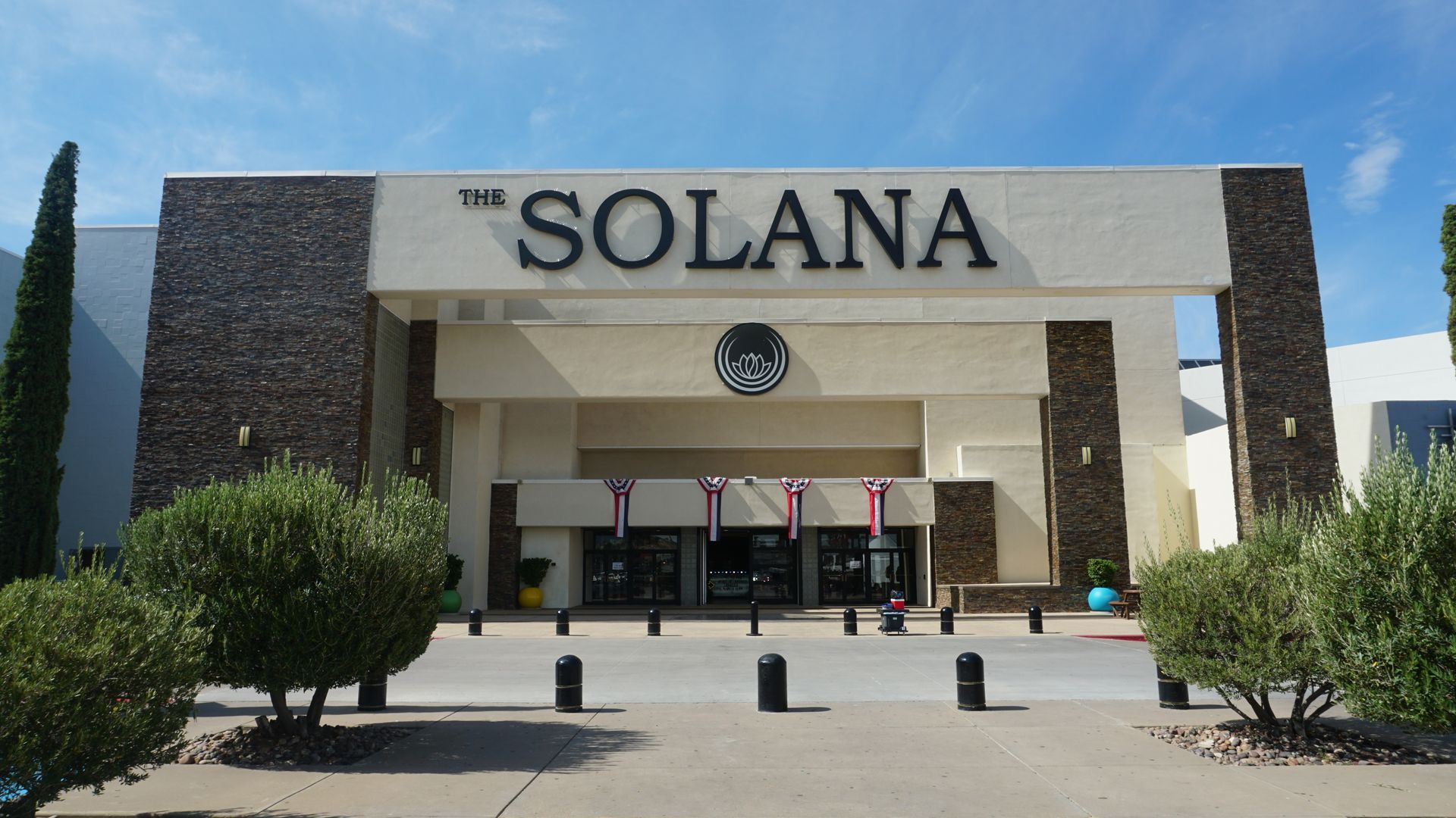 Solana building entrance with large sign, columns, and desert landscaping under a clear blue sky