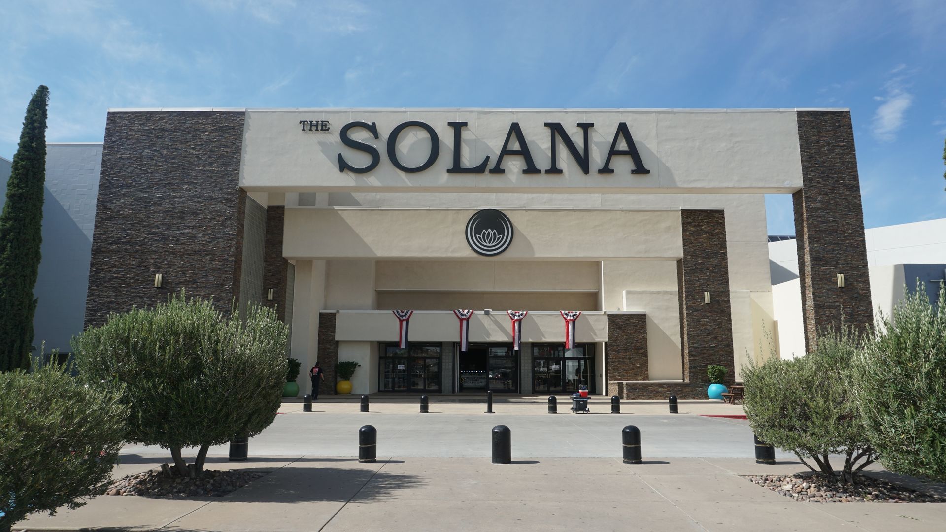 Front entrance of Solana building with white columns, stone walls, and desert landscaping under a clear sky