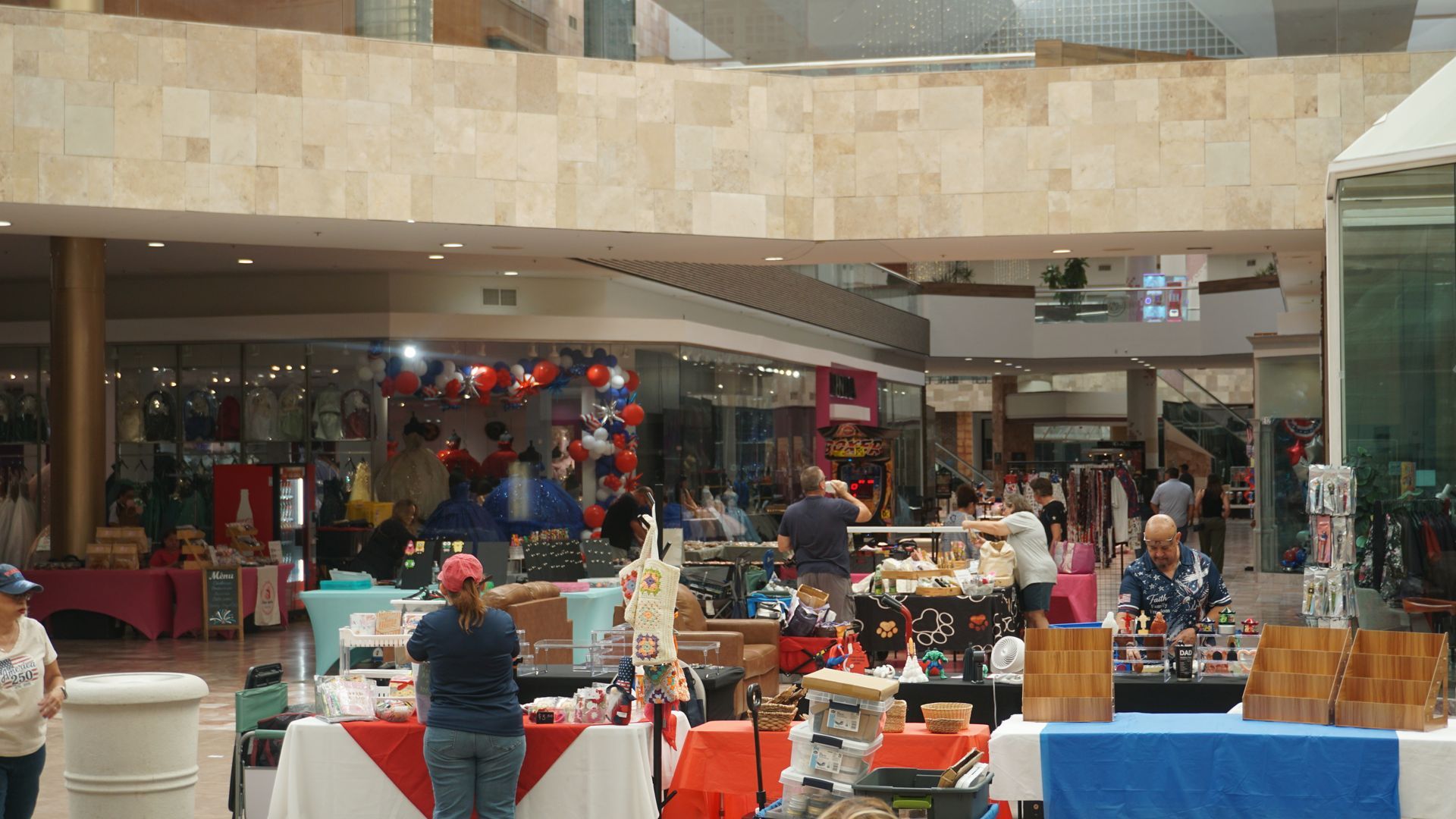 Indoor market with colorful stalls, shoppers, and hanging decorations in a mall-like atrium