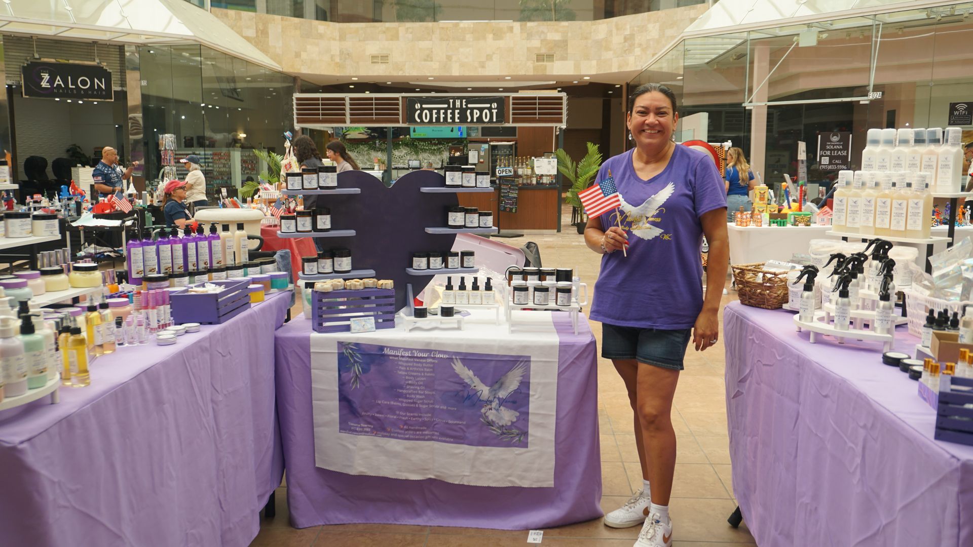 Woman posing at a cosmetics booth with purple tablecloths in an indoor market
