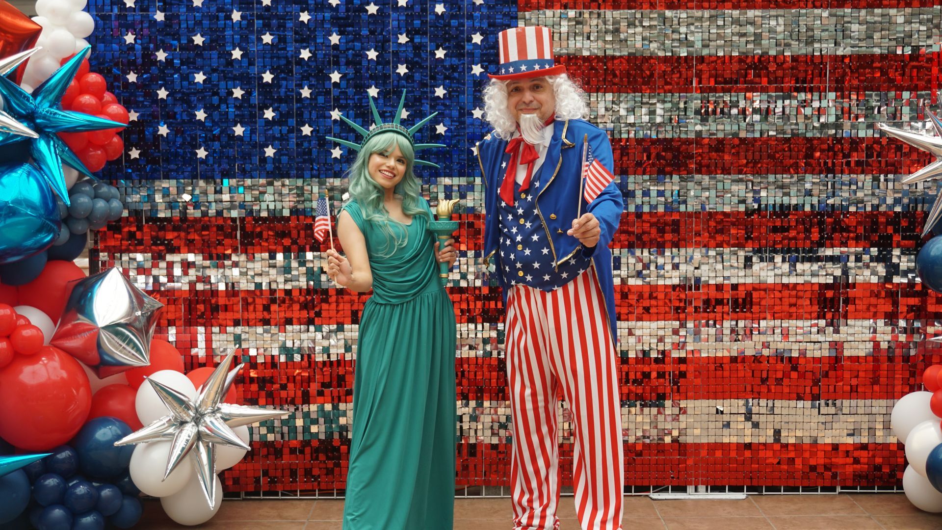 Woman and Uncle Sam figure posing before a patriotic American flag balloon backdrop